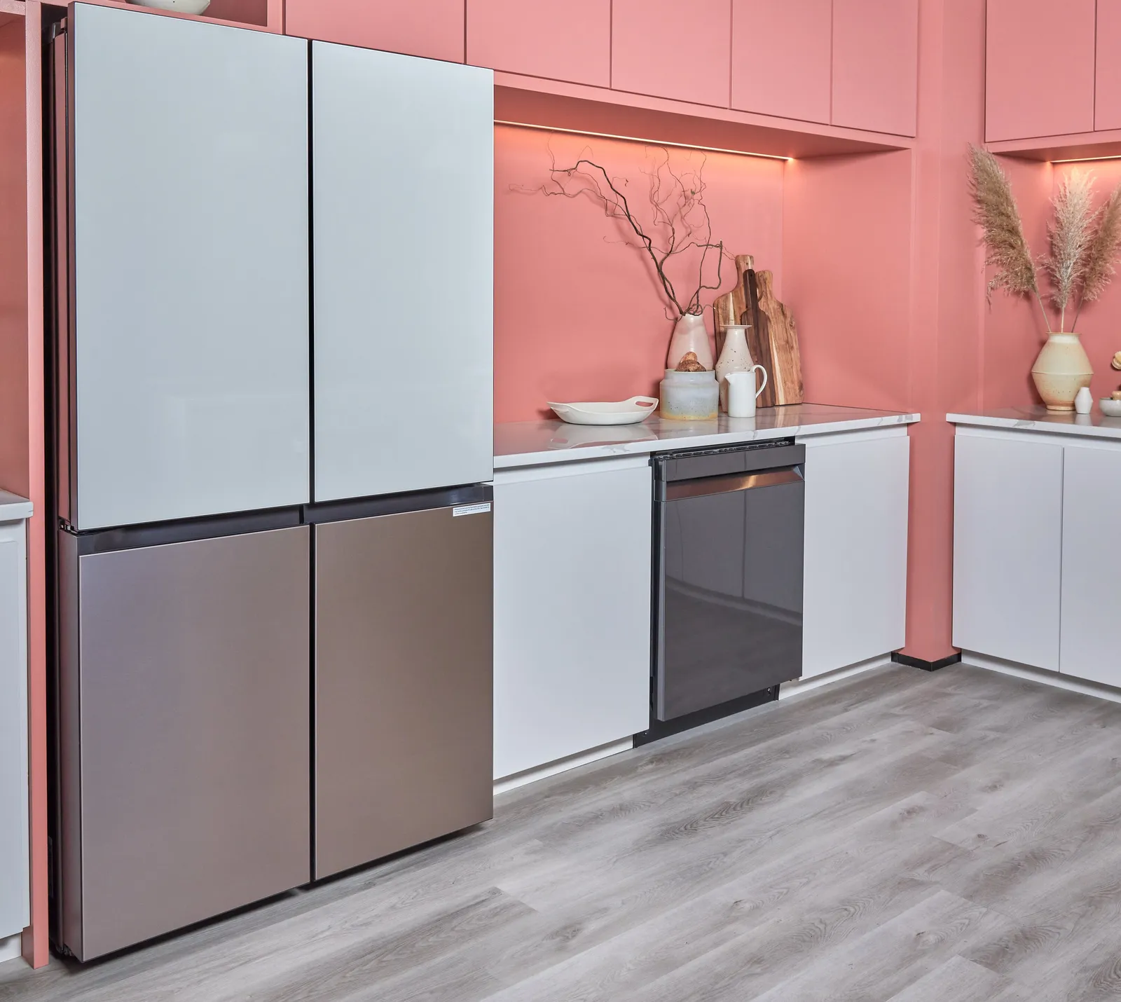 pink kitchen with a four-door glass and steel refrigerator, dishwasher, white cabinets and dried grasses in a vase