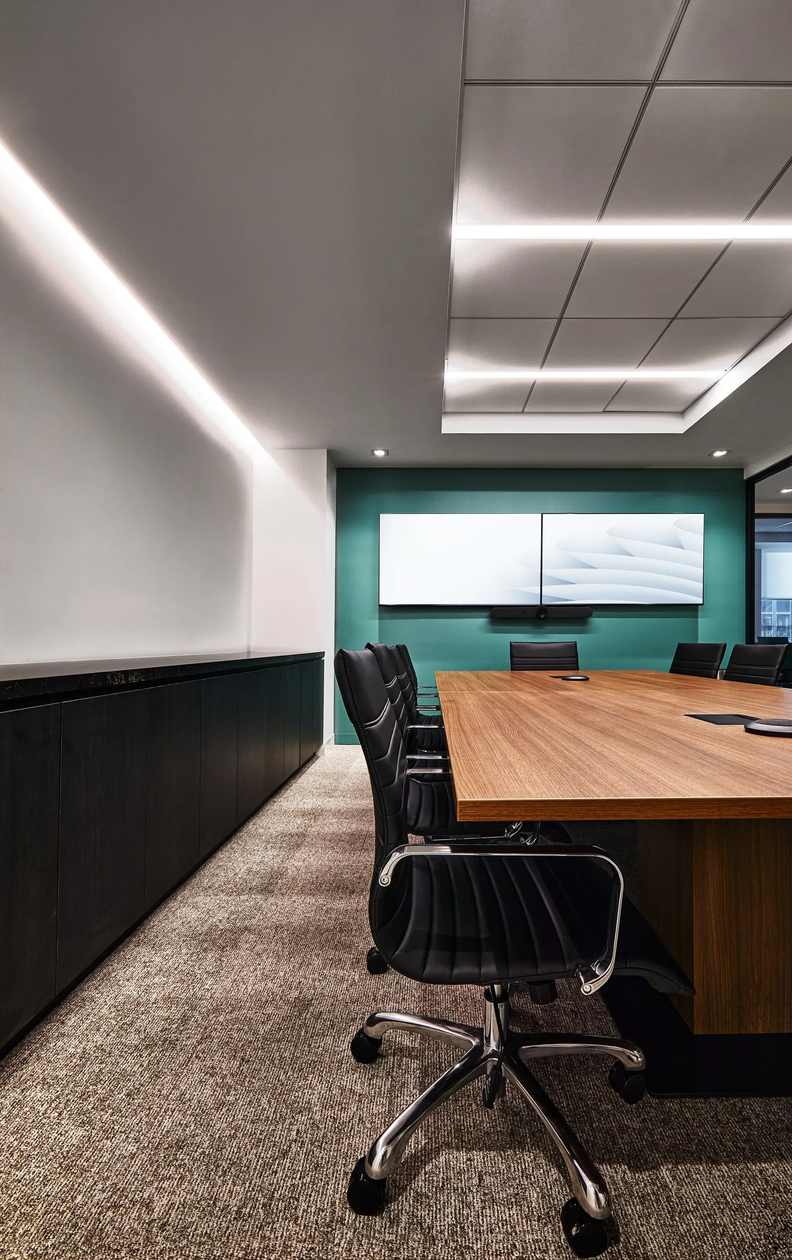 conference room end wall painted teal, black cabinet along the left, recessed strip lights overhead