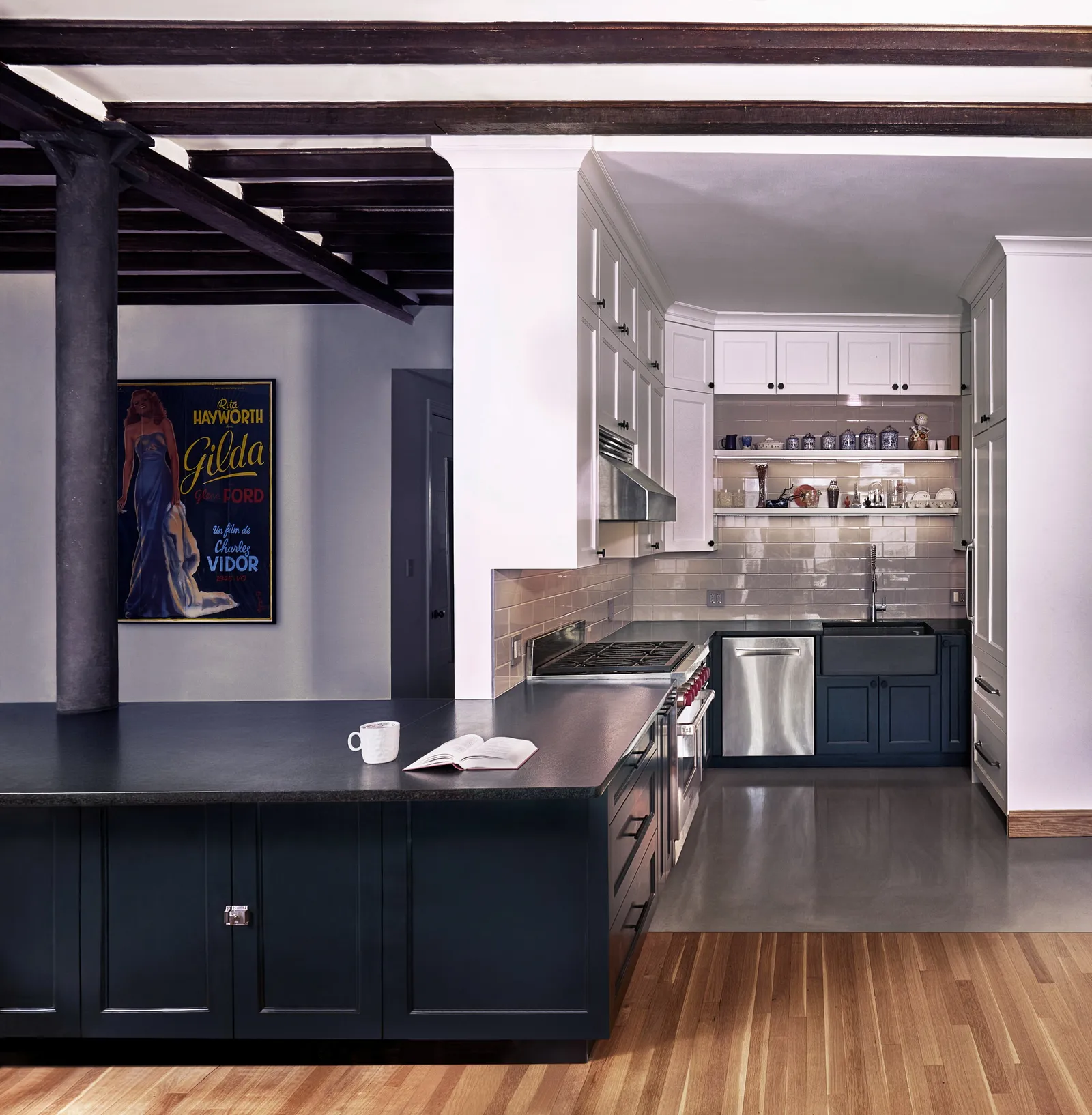 kitchen with a dark counter peninsula, navy cabinets, a column and a framed "gilda" movie poster