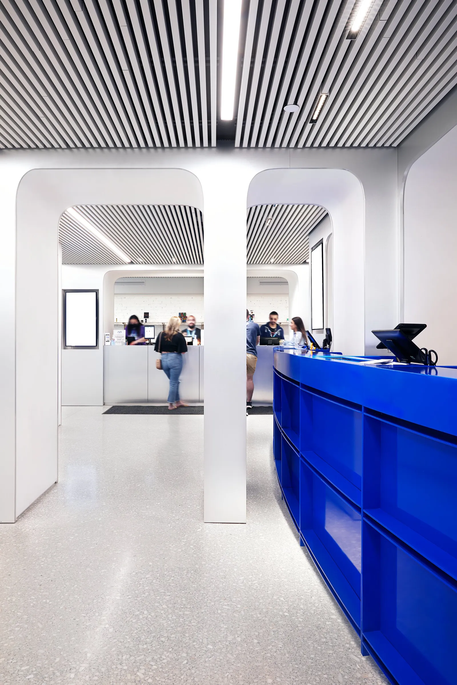 vertical view past a white column toward customers at a blue counter on the right