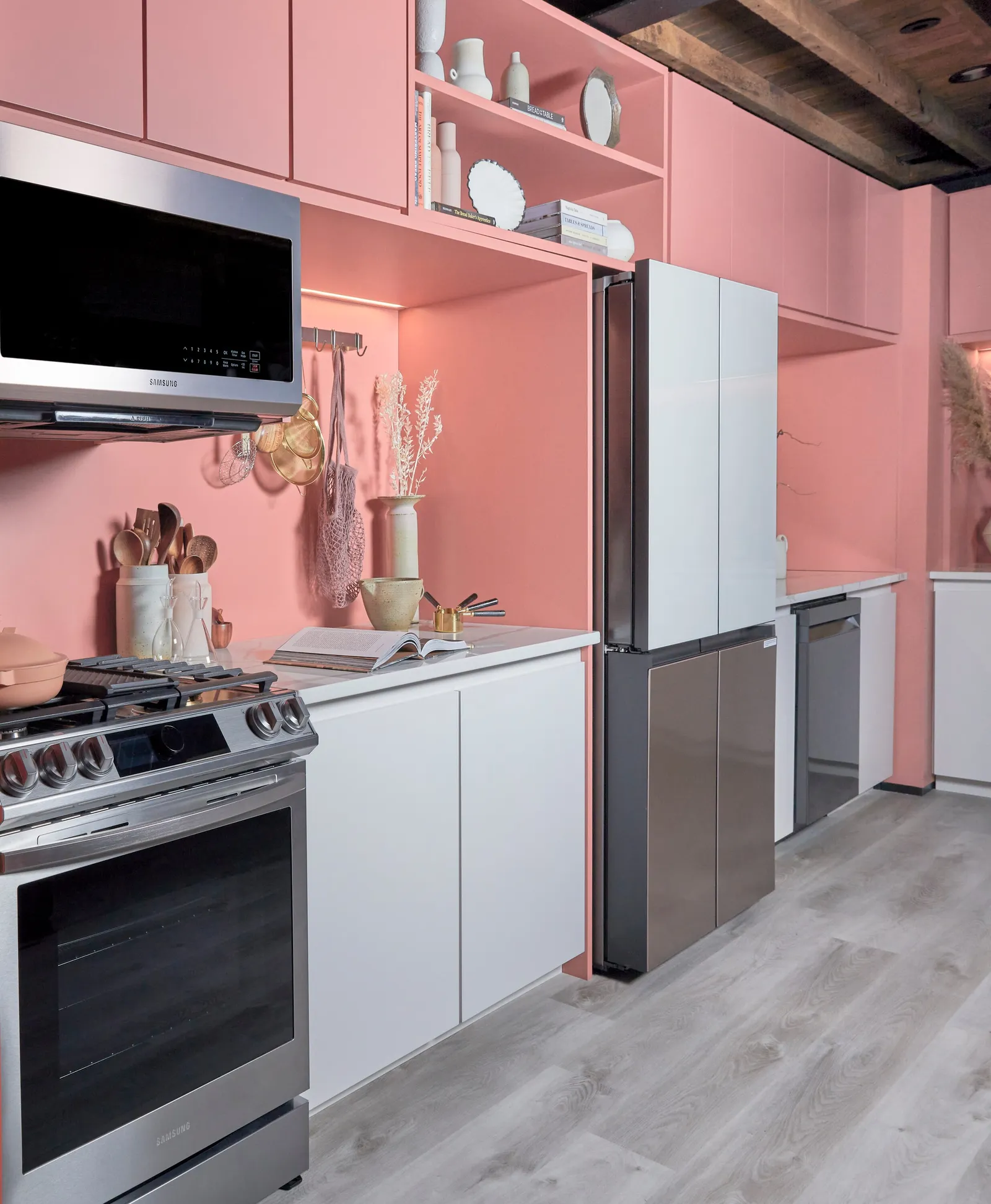 angled view of range and microwave in the pink kitchen with refrigerator and dishwasher beyond