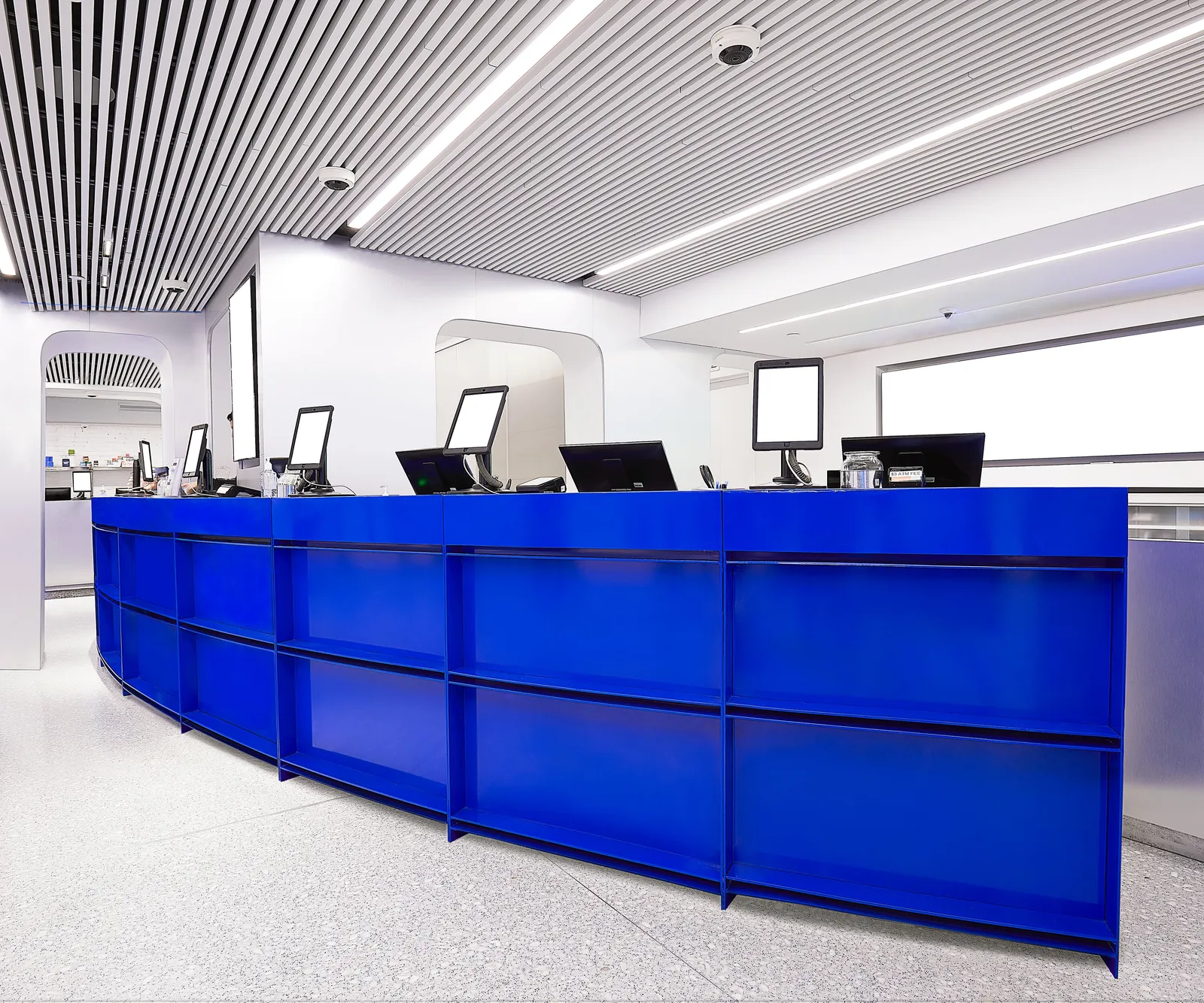 low angle along the sweeping blue counter, monitors in a row and a slatted ceiling above