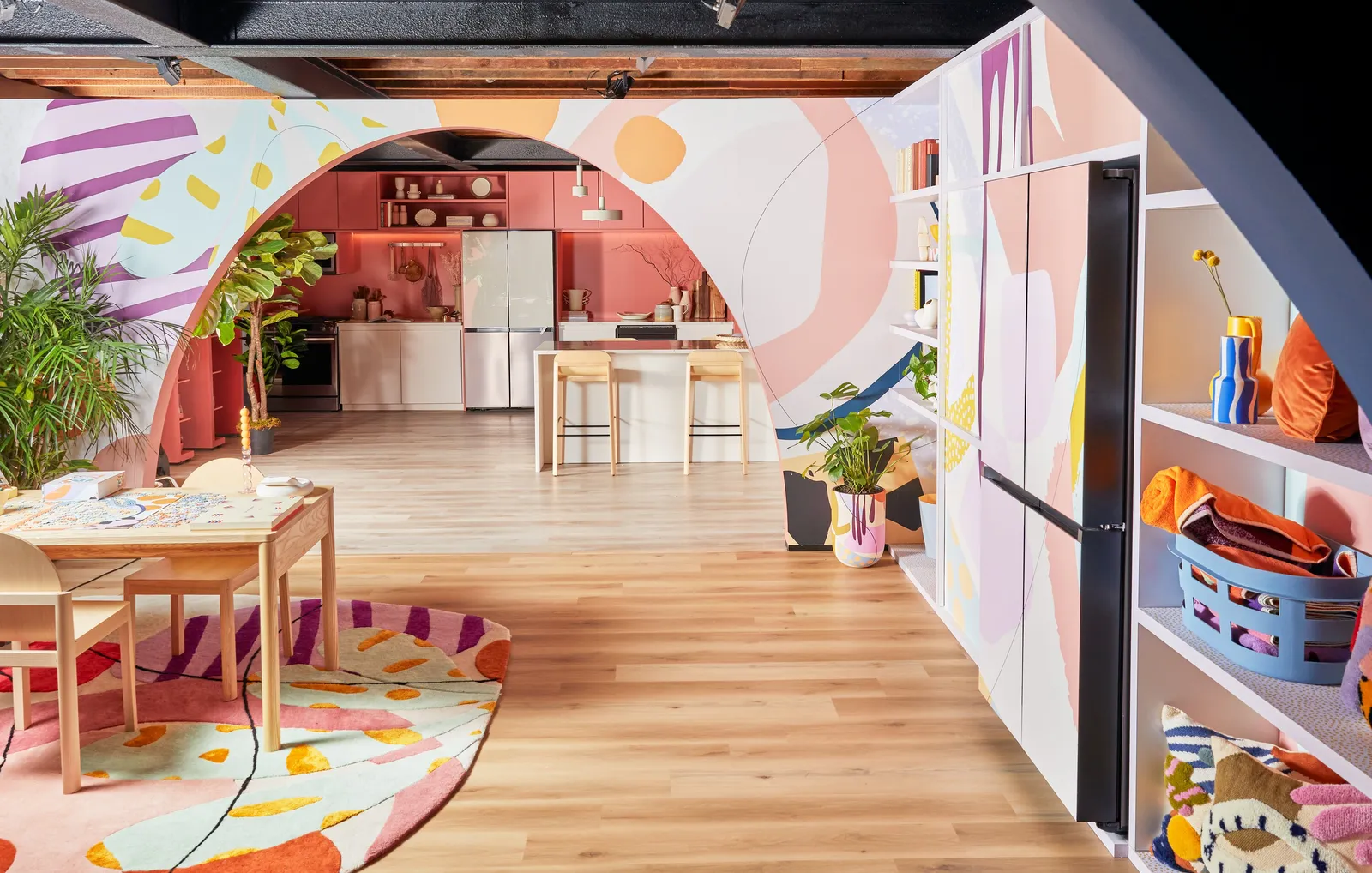 view through a painted arch to the pink kitchen, with a table and round patterned rug in front
