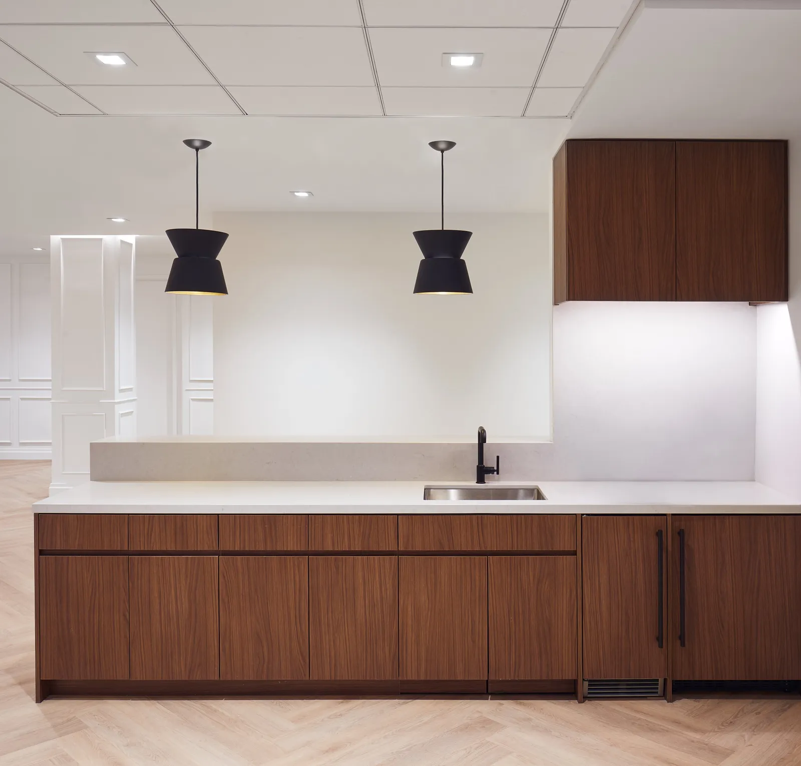 kitchen counter with sink, walnut cabinets and two black hourglass pendant lamps above