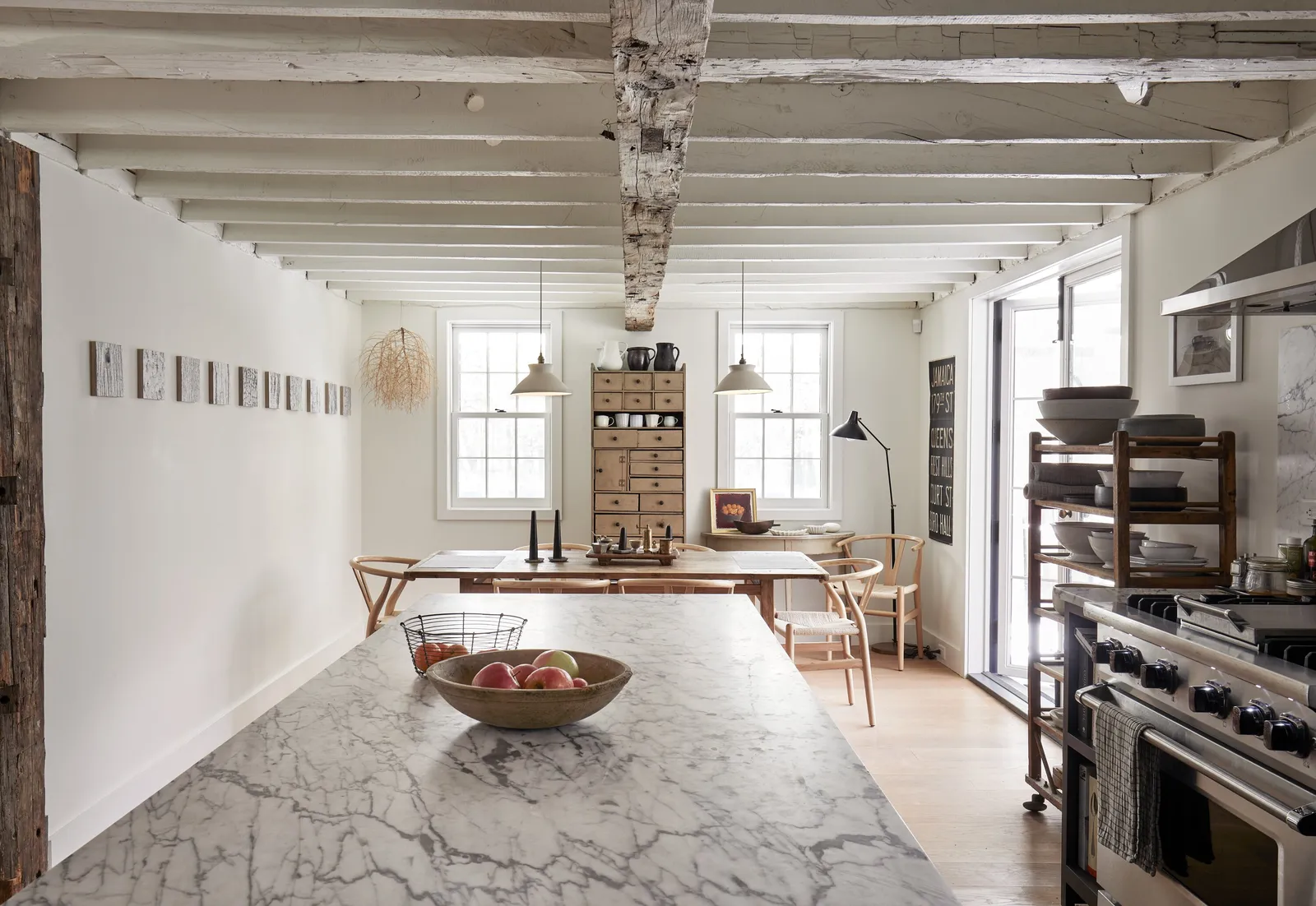 marble island in the foreground, looking down the long room to a dining table and range under old beams