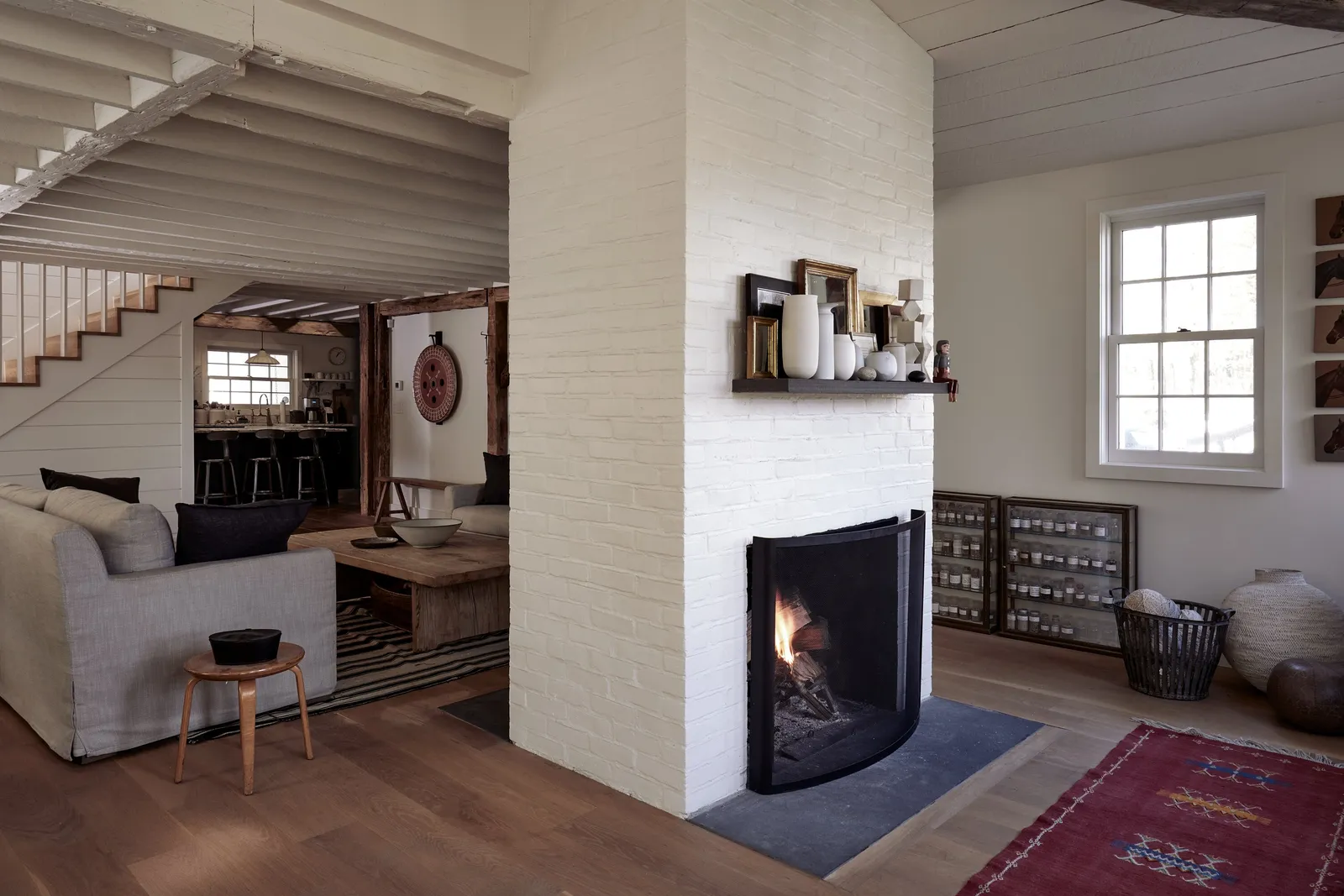 living room with a white brick fireplace, a gray sofa and a red patterned rug