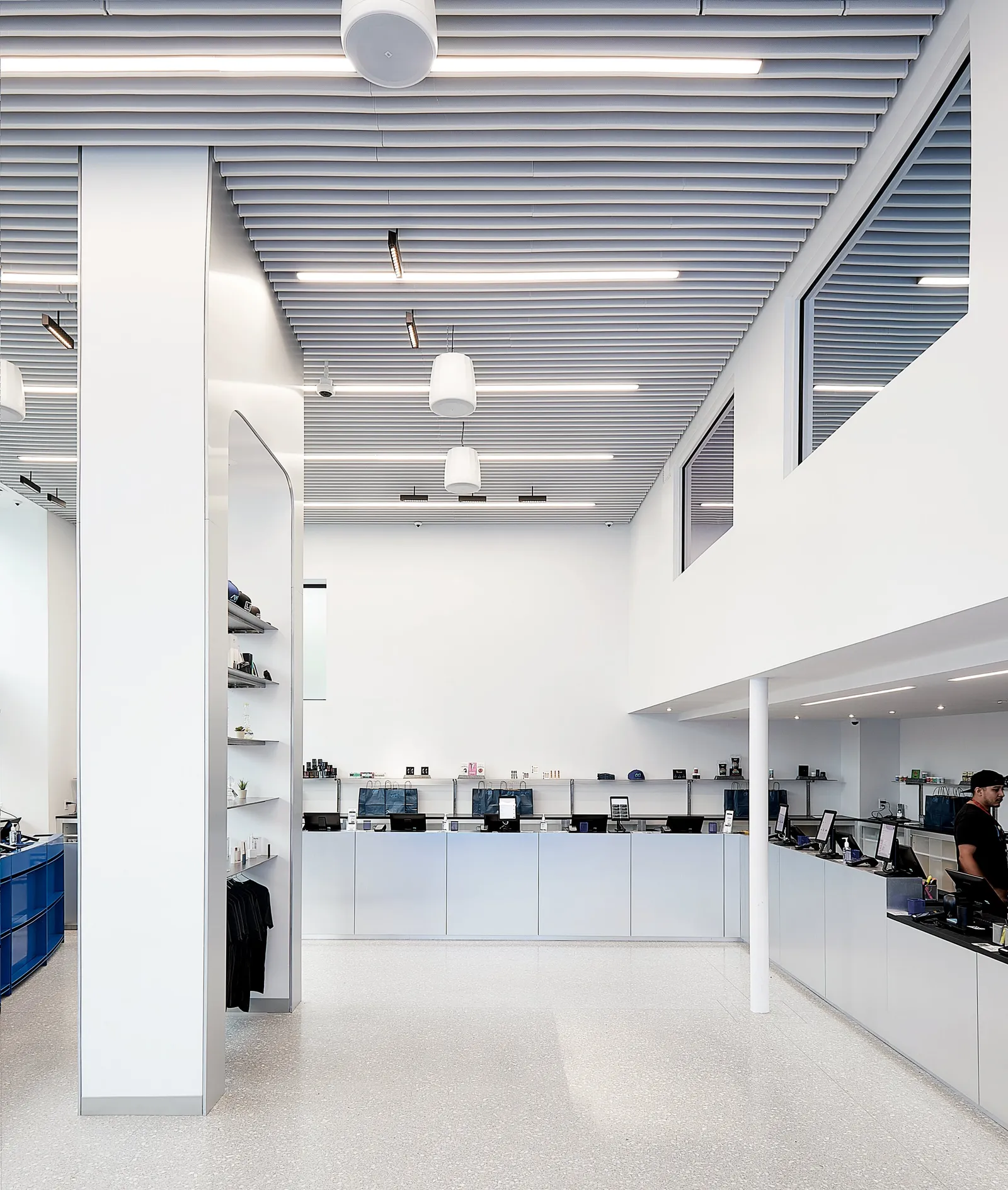 vertical view across the open floor to a silver counter and an employee, under a high slatted ceiling