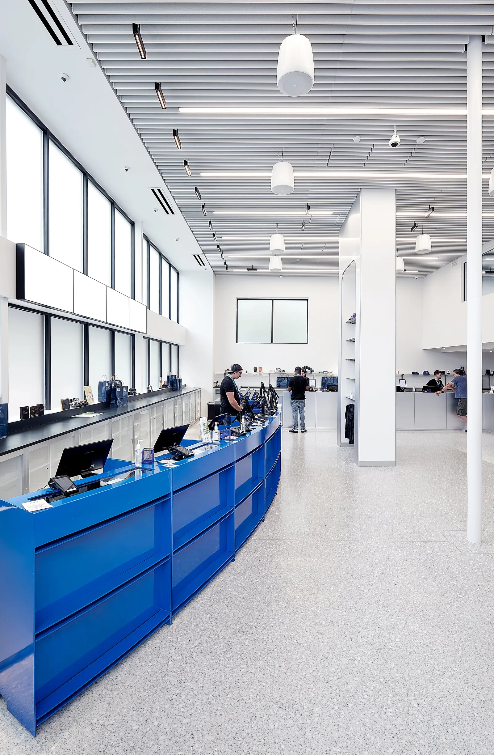 long view down the curved blue counter at left with staff and customers, tall windows and a white column
