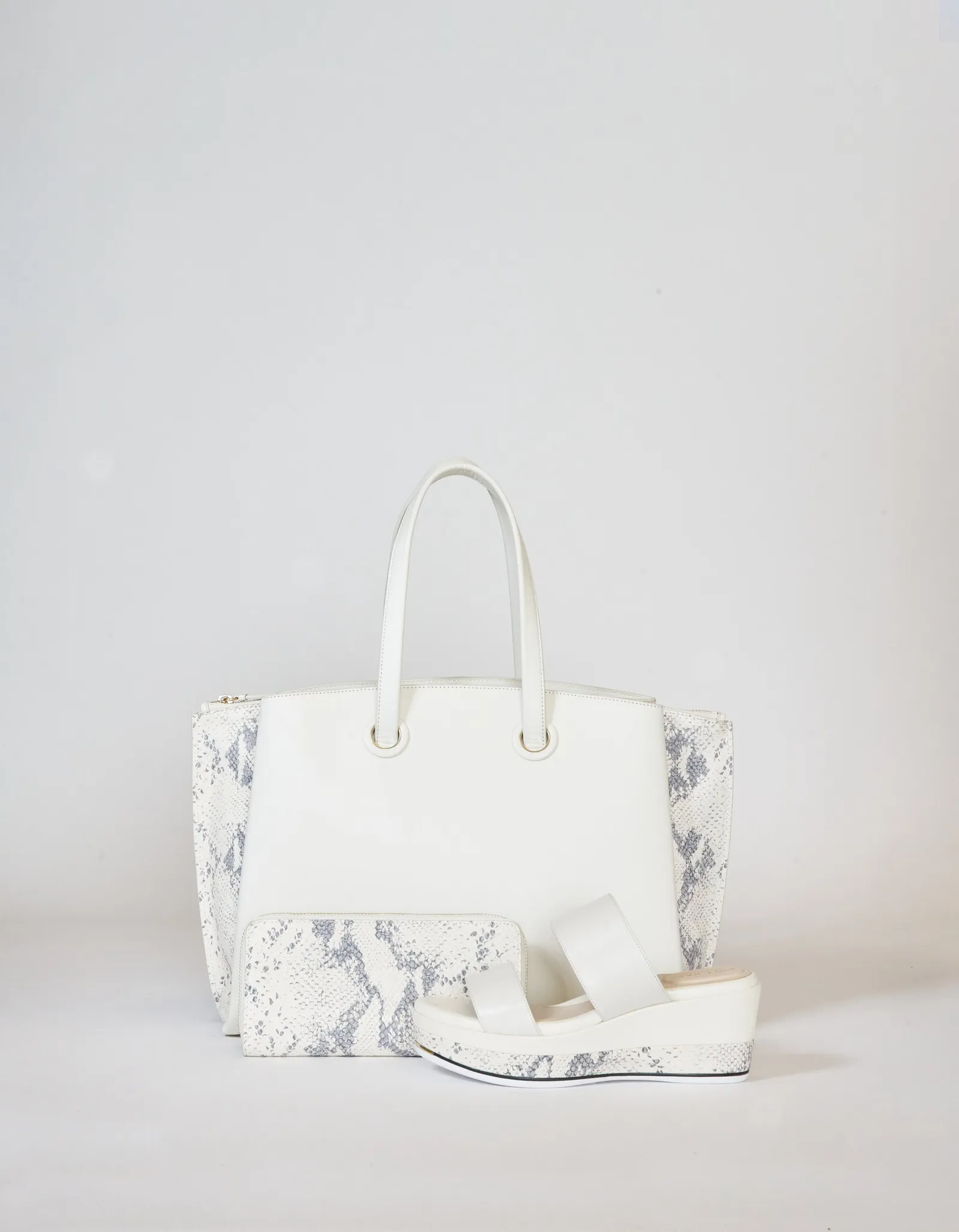 a tall white tote with a snakeskin-print side panel, a matching zip pouch and a white platform sandal