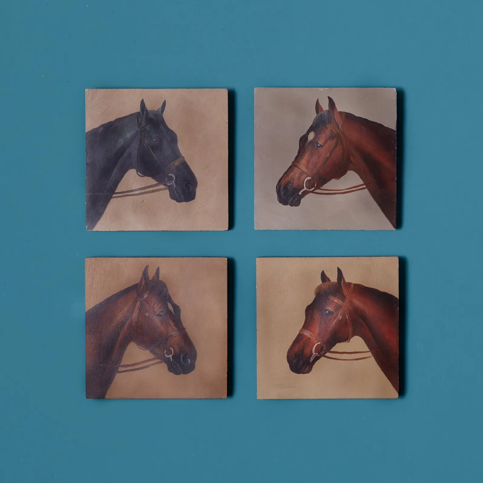 four small painted portraits of horse heads, black and chestnut brown, in a two-by-two grid on a deep teal background