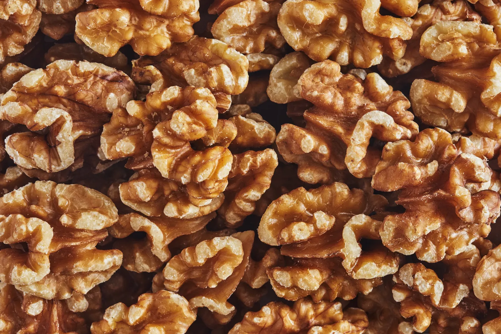 overhead scatter of trail mix ingredients, including nuts, dried berries, banana chips, chocolate and pumpkin seeds, across a white surface