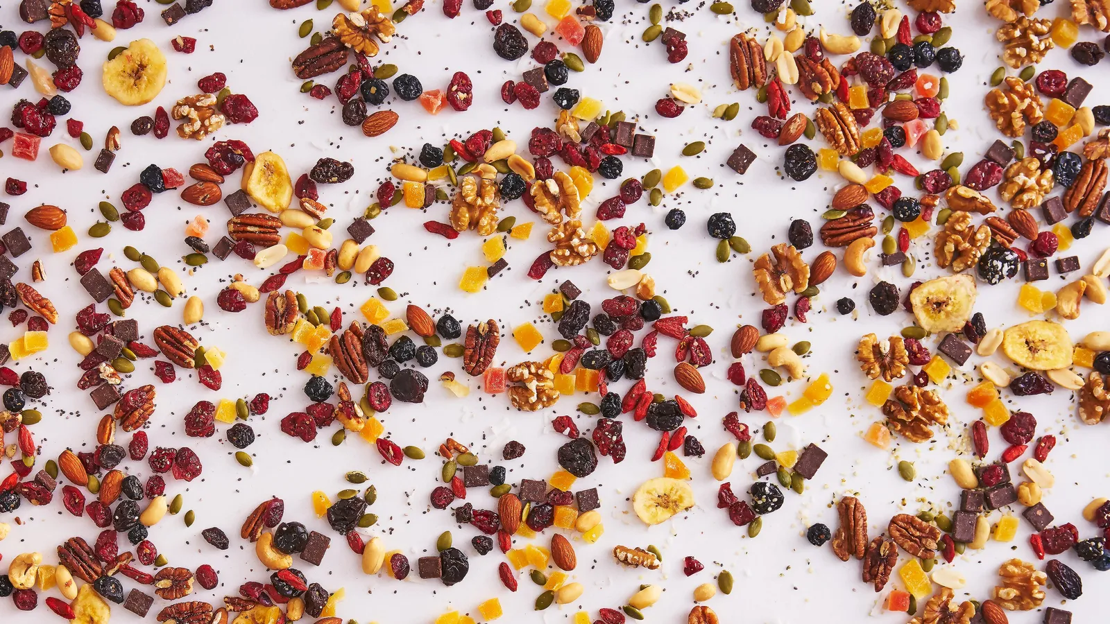 lineup of snack packages, including trail mix, smoothie mixes, salad toppers, spice grinders and energy bars, on a white marble counter