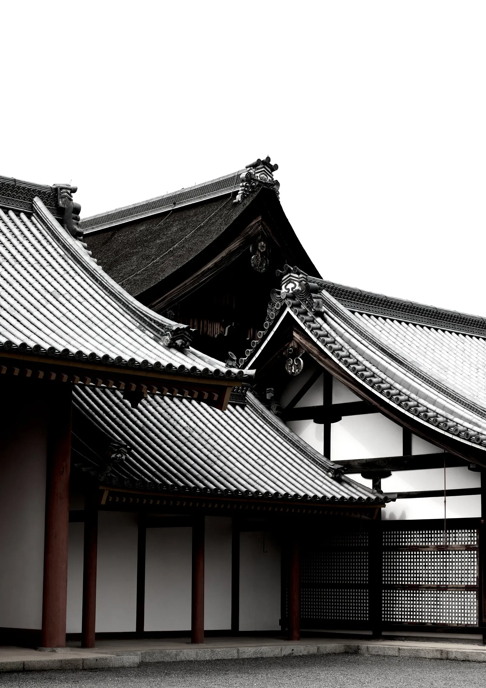 black and white view of overlapping tiled temple rooftops with dark red posts and white walls against a blank sky