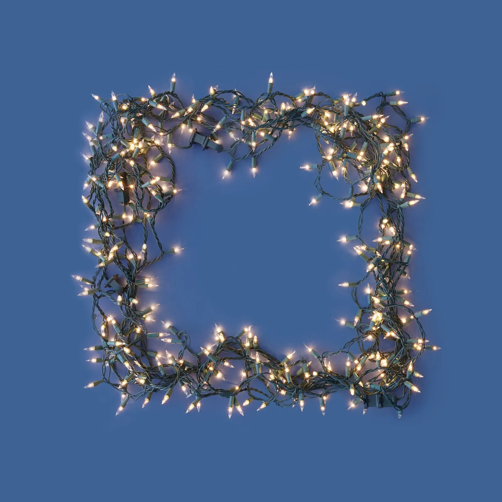 tangled string of warm white Christmas lights forming a hollow square on a deep blue background